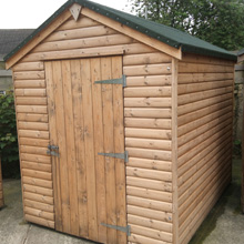 large log shed with black felt roof